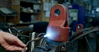 Arbeiter erwärmt massives Metallbauteil mit einem Gasbrenner in einer Werkstatt