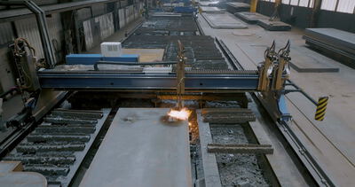 Automatisierte Brennschneidmaschine schneidet eine dicke Stahlplatte in einer Industriehalle mit hellem Funkenflug