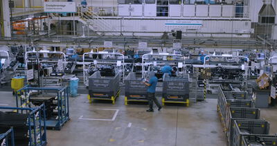 Blick auf eine strukturierte Cockpitmontage mit Arbeitern in einer großen Automobilfabrik
