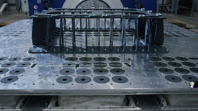 Detailaufnahme einer metallischen Montageplatte mit aufgeschraubtem technischem Trägergestell auf einem Prüfstand Detailaufnahme einer metallischen Montageplatte mit aufgeschraubtem technischem Trägergestell auf einem Prüfstand, Bauteil,