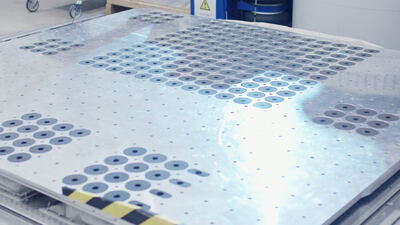 Detailaufnahme einer vibrierenden Aluminium-Gleitplatte im Prüflabor
