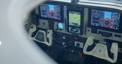 Detaillierte Innenansicht eines modernen Flugzeugcockpits mit aktiven digitalen Displays und Doppelsteuerhorn