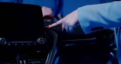 Expertin prüft die Spaltmaße am Infotainment-Bildschirm eines Autos unter blauem Licht
