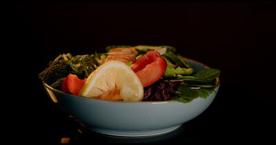Frische Bowl mit Lachs, Avocado und Brokkoli vor schwarzem Hintergrund auf einem Drehteller in Nahaufnahme