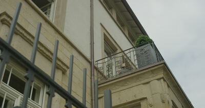 Froschperspektive von einem Balkon mit verziertem Metallgeländer an einer klassischen Sandsteinfassade