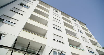 Froschperspektive von einer modernen weißen Wohnhausfassade mit Balkonen gegen den blauen Himmel, Gebäude, Architektur und