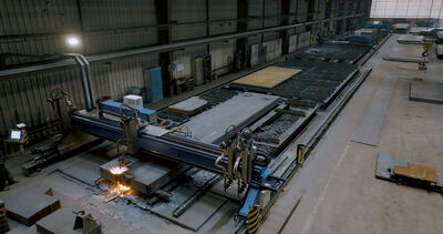 Große CNC-Brennschneidanlage bei der automatisierten Bearbeitung von massiven Stahlplatten in einer Werkhalle
