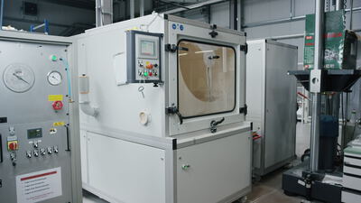 Große industrielle Prüfkammer mit Bedienfeld und rotierendem Scheibenwischer in einer Fabrikhalle