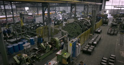 Große rotierende Korbverseilmaschine zur Fertigung von Stahlseilen in einer Industriehalle