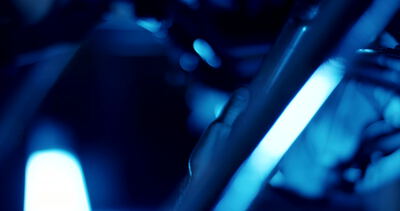 Hand prüft mechanische Metallstreben unter intensivem blauem Licht