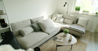 Helles und modernes Wohnzimmer mit gemütlichem grauem Ecksofa, Couchtisch und Dekoration