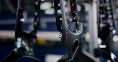 Hergestellte Bauteile mit Carbonstruktur hängen an einer Halterung in einer Fabrik