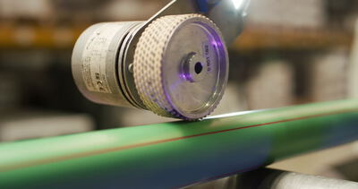 Industrielle Markiermaschine beim Bedrucken eines grünen Kunststoffrohrs