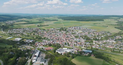 Luftaufnahme einer deutschen Ortschaft umgeben von Feldern und Waldflächen