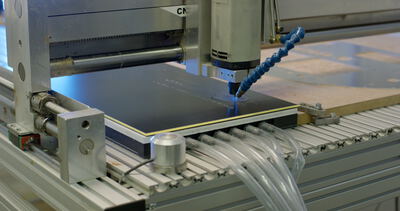 Moderne CNC-Fräse bei der präzisen Bearbeitung einer dunklen Kunststoffplatte in einer industriellen Fertigung
