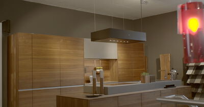 Moderne Luxusküche mit Holzfronten und freihängender Dunstabzugshaube über einer Kochinsel