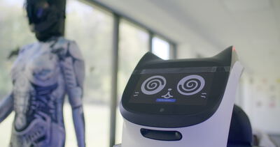 Moderner Serviceroboter mit Katzenohren und digitalem Displaygesicht in heller Innenraumumgebung neben einer Schaufensterpuppe