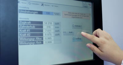 Nahaufnahme einer Hand bei der Bedienung einer industriellen Maschinensteuerung via Touchscreen