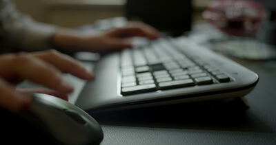 Nahaufnahme einer Person beim Arbeiten am Computer mit Maus und Tastatur