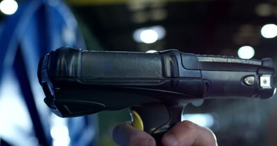Nahaufnahme eines Handscanners bei der Erfassung von Barcodes in einer Industriehalle
