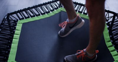 Person beim Training mit Sportschuhen auf einem kleinen Fitnesstrampolin