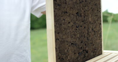 Person entnimmt eine Korkplatte aus einem Bienenstock im Freien