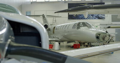 Privatjet in der Wartungshalle einer Flugzeugwerft mit Blick auf geöffnete Triebwerksverkleidungen und technisches Equipment