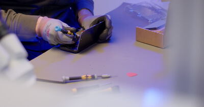 Reparatur eines Smartphones mit Feinmechanik-Werkzeug an einem Arbeitstisch