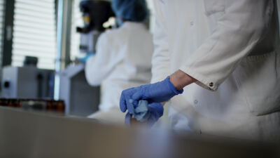 Laborantin reinigt Glasfläschchen in der Pharmaproduktion