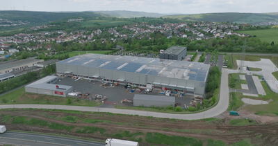 Drohnenaufnahme eines Industriegebäudes mit Solaranlage und Parkplatz