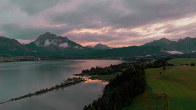 Luftaufnahme über einen Alpensee mit Bergen in der Abenddämmerung Luftaufnahme über einen Alpensee mit Bergen in der Abenddämmerung, Drohnenaufnahme, Bergsee und Landschaft als 4K Stockvideo