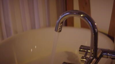 Fließendes Wasser läuft aus einem verchromten Wasserhahn
