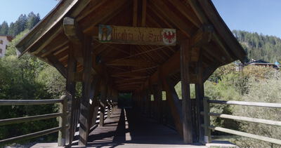 Überdachte Holzbrücke, Fahrt vom Eingang durch den sonnigen Brückengang, überdachte Brücke, Fußgängerbrücke und Holzbau als