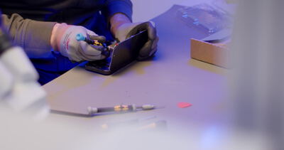 Hände reparieren ein Smartphone mit Präzisionswerkzeug
