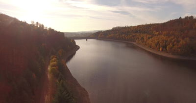 Luftaufnahme weiter Stausee mit ferner Brücke im Herbst