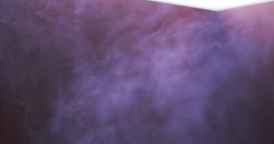 Violette Nebelschwaden treiben vor hellem Licht durch einen dunklen Raum