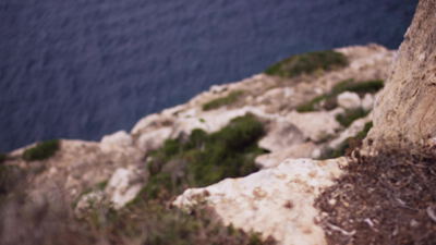 Blick von einer felsigen Steilkueste hinab auf das blaue Meer