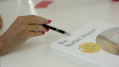 Hand mit Stift zeigt auf eine weiße Dokumentenmappe am Tisch Hand mit Stift zeigt auf eine weiße Dokumentenmappe am Tisch, Notfallmappe, Büro und Beratung als 4K Stockvideo