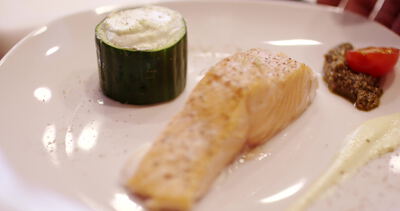 Gebratenes Lachsfilet mit Sahnesauce auf weißem Teller angerichtet