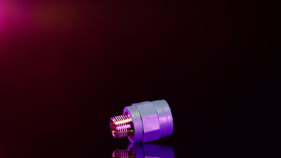 Violettes Metallverbindungsstück dreht sich vor dunklem Hintergrund