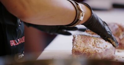 Hand massiert Gewürzmischung in großen Schweinebraten auf weißem Brett