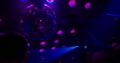 Glitzernde Discokugel und bunte Lichtpunkte im dunklen Nachtclub