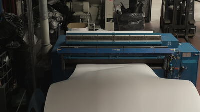 Materialbahn läuft durch eine Maschine mit Reinigungsbürste Materialbahn läuft durch eine Maschine mit Reinigungsbürste, Vliesmaterial, Bahn durch Maschine und Industriemaschine als 4K