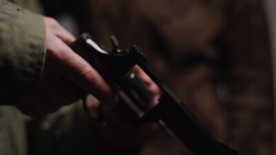 Hand hält einen geladenen Revolver in einem dunklen Raum