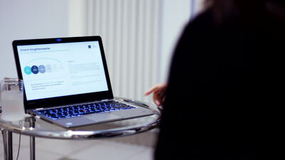 Person bedient einen Laptop mit Firmenwebsite am Glastisch, Notebook, Unternehmenswebsite und Webseite bedienen als 4K