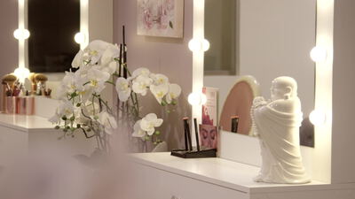 Beleuchteter Schminkspiegel mit Pinseln und weißer Orchidee