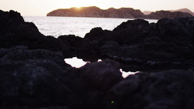Sonne geht hinter felsiger Küste über dem Meer unter