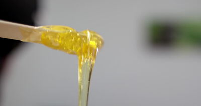 Goldene Zuckerpaste zieht Fäden an einem Holzspatel