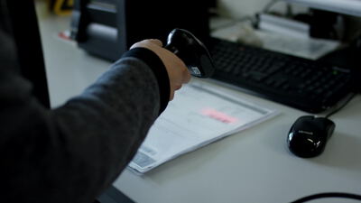 Hand scannt einen Beleg mit einem Barcodescanner am Schreibtisch