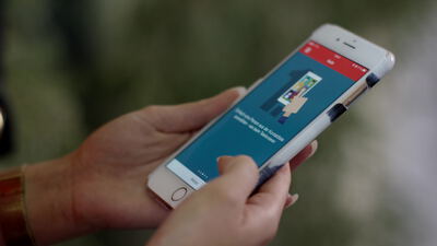 Hände bedienen eine bunte App auf einem weißen Smartphone